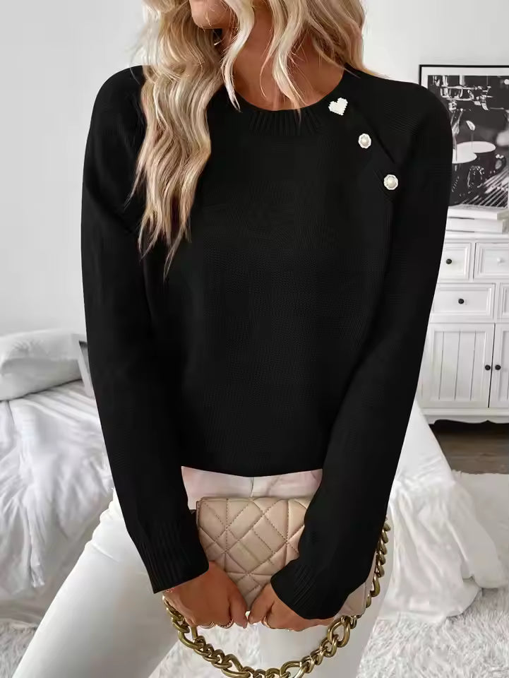 Nora Black knit sweater featuring diagonal button accents, a round neckline, and relaxed fit