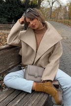 Nora Khaki cropped double-breasted jacket shown seated with oversized notched lapels, relaxed shoulders, long sleeves, and button-front styling