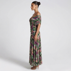 Side view of the Nova Evening Maxi Dress with Off Shoulder and Ruched Waist Style in green floral, showcasing the off-the-shoulder silhouette, flattering ruched waist, and graceful floor-length drape. Designed by Bella Hudson.