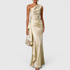 Full-length view of the Odessa Maxi Evening Dress Satin One-Shoulder Ruffle Style in champagne, showcasing the elegant draped silhouette, satin finish, and floor-length design. Designed by Bella Hudson.