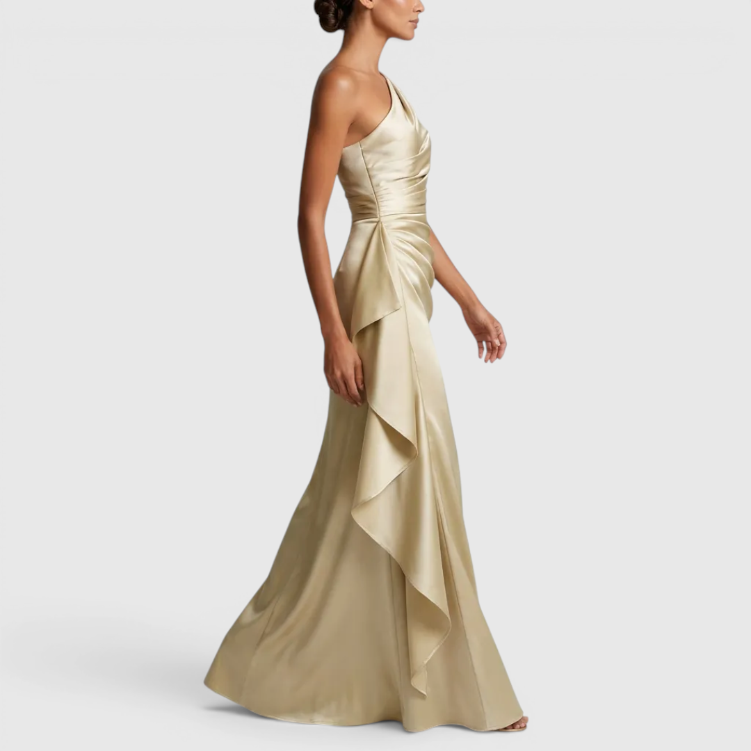 Side view of the Odessa Maxi Evening Dress Satin One-Shoulder Ruffle Style in champagne, showcasing the one-shoulder neckline, flowing satin fabric, and graceful floor-length silhouette. Designed by Bella Hudson.