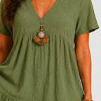 Close-up detail view of olive green tiered mini dress with V-neckline and necklace accessory by BELLA HUDSON