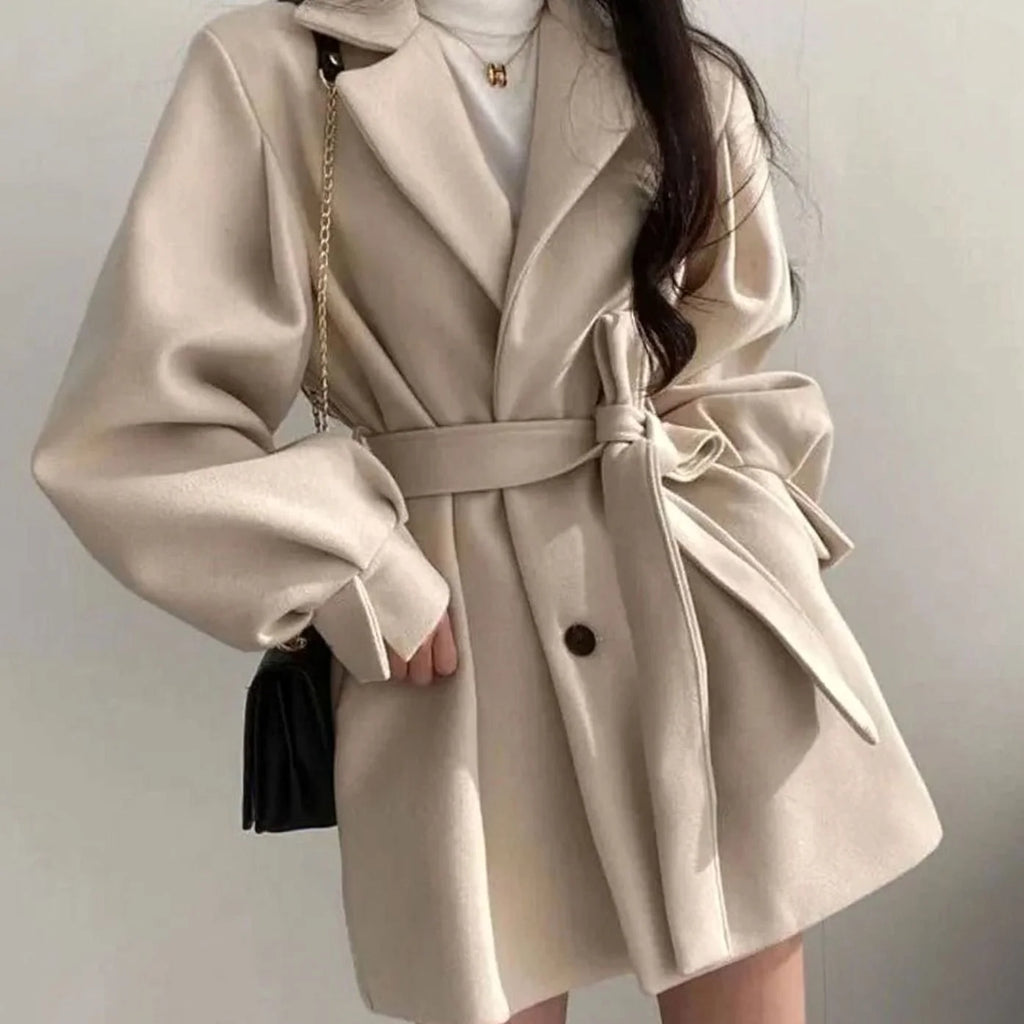 Olivia Beige A-line short coat featuring a tie waist belt, wide lapel collar, relaxed sleeves, and front button detailing