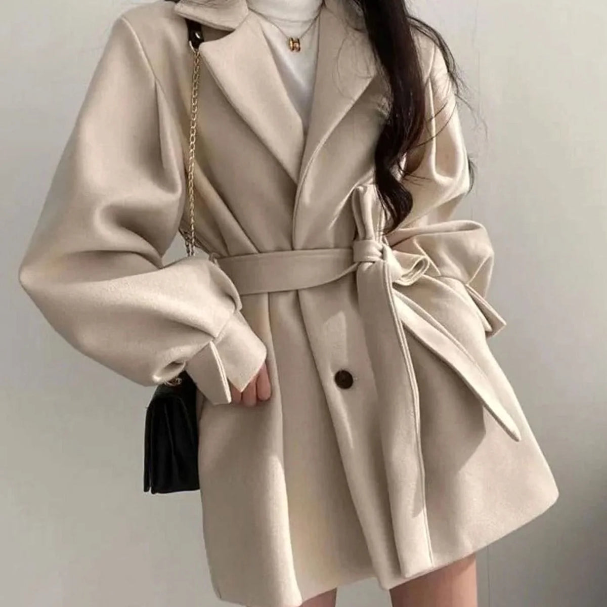 Olivia Beige A-line short coat featuring a tie waist belt, wide lapel collar, relaxed sleeves, and front button detailing
