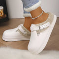Paige White mule slippers with plush faux-fur lining, decorative buckle straps, rounded closed toes, and thick soles, shown on feet