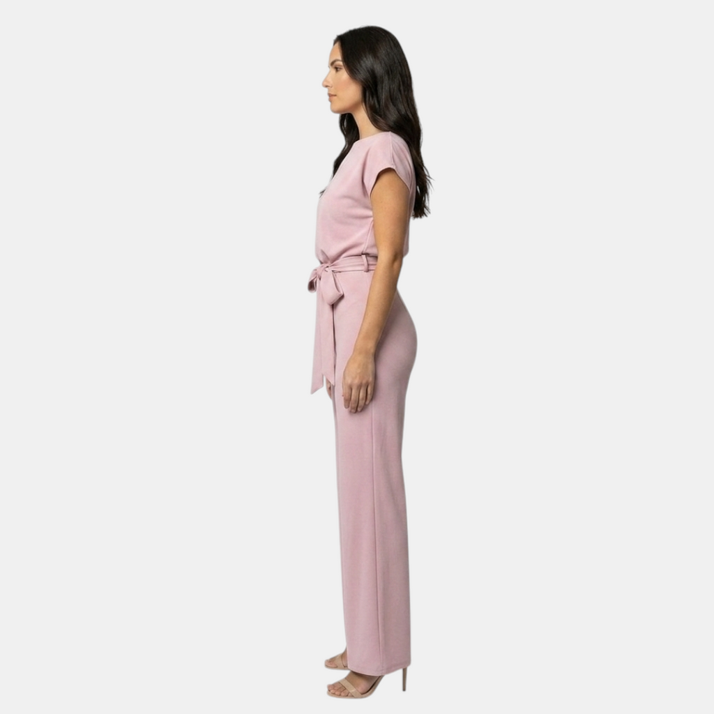 Side view of the Paloma Jumpsuit Wide-Leg Tie-Waist in pink, showcasing the cap sleeves, tie-waist detail, and flowing wide-leg silhouette. Designed by Bella Hudson.