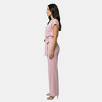 Side view of the Paloma Jumpsuit Wide-Leg Tie-Waist in pink, showcasing the cap sleeves, tie-waist detail, and flowing wide-leg silhouette. Designed by Bella Hudson.