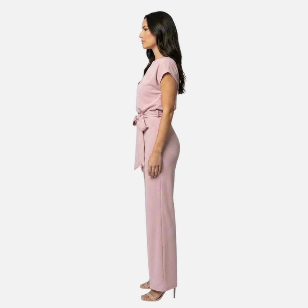 Side view of the Paloma Jumpsuit Wide-Leg Tie-Waist in pink, showcasing the cap sleeves, tie-waist detail, and flowing wide-leg silhouette. Designed by Bella Hudson.