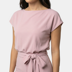 Close-up detail of the Paloma Jumpsuit Wide-Leg Tie-Waist in pink, featuring the round neckline, cap sleeves, elastic waistband, and self-tie waist belt. Designed by Bella Hudson.