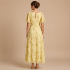 Back view of the Patrice Floral Chiffon Maxi Dress with flutter sleeves in yellow. Designed by Bella Hudson.