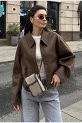 Quinn Brown collared zip-up jacket worn open over a white tee with light gray jeans and a crossbody bag.