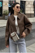 Quinn Brown collared zip-up jacket worn open over a white tee with light gray jeans and a crossbody bag.