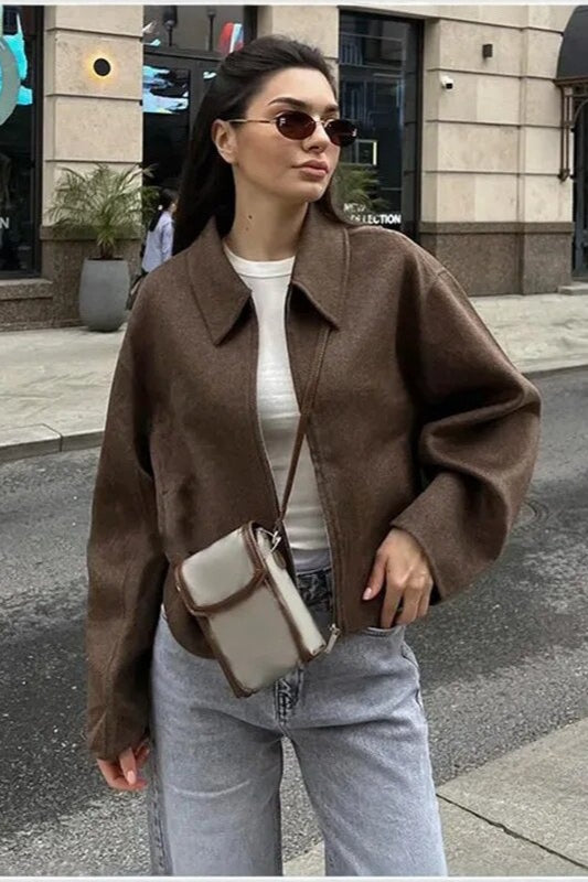 Quinn Brown collared zip-up jacket worn open over a white tee with light gray jeans and a crossbody bag.