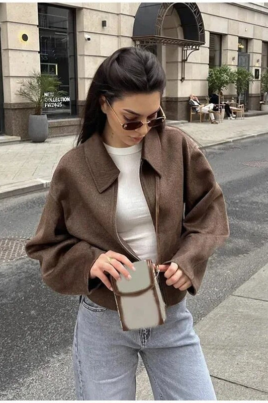 Quinn Brown cropped zip-up jacket styled with a white ribbed tee and jeans, showing the collar and loose sleeves.
