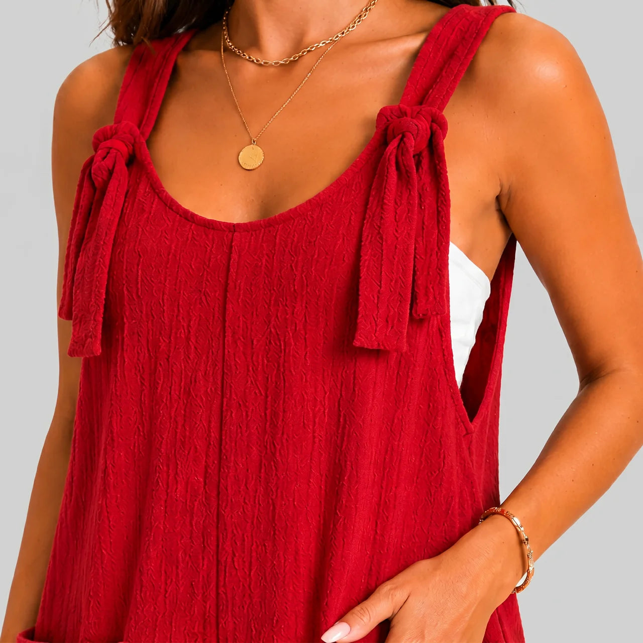 Close-up detail view of red sleeveless short jumpsuit with tie shoulder straps by BELLA HUDSON