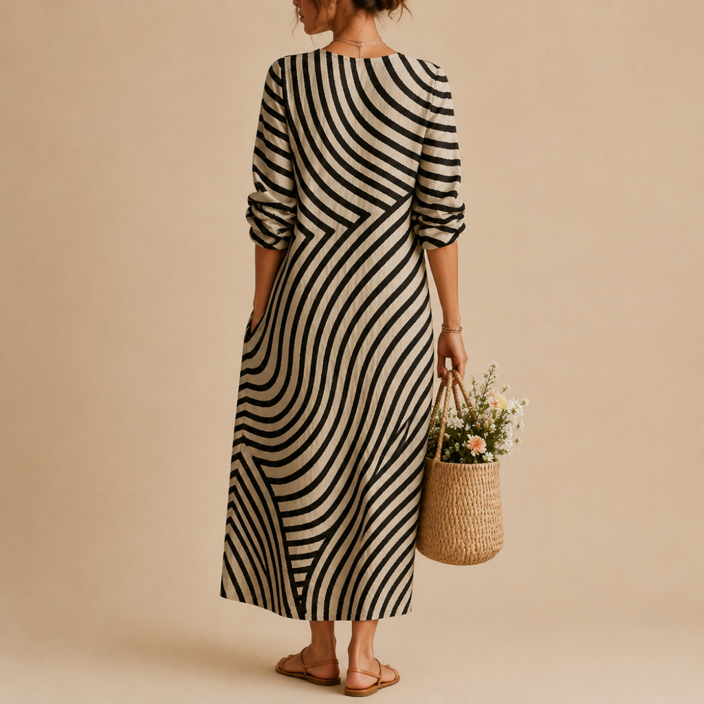 Back view of the Romy Striped Lightweight Vintage Midi Dress featuring an abstract striped patchwork pattern, long sleeves, and a relaxed flowing midi-length silhouette. Designed by Bella Hudson.