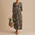 Romy Striped Lightweight Vintage Midi Dress featuring an abstract striped patchwork pattern, V-neckline, long sleeves, practical pockets, and a relaxed midi-length silhouette. Designed by Bella Hudson.