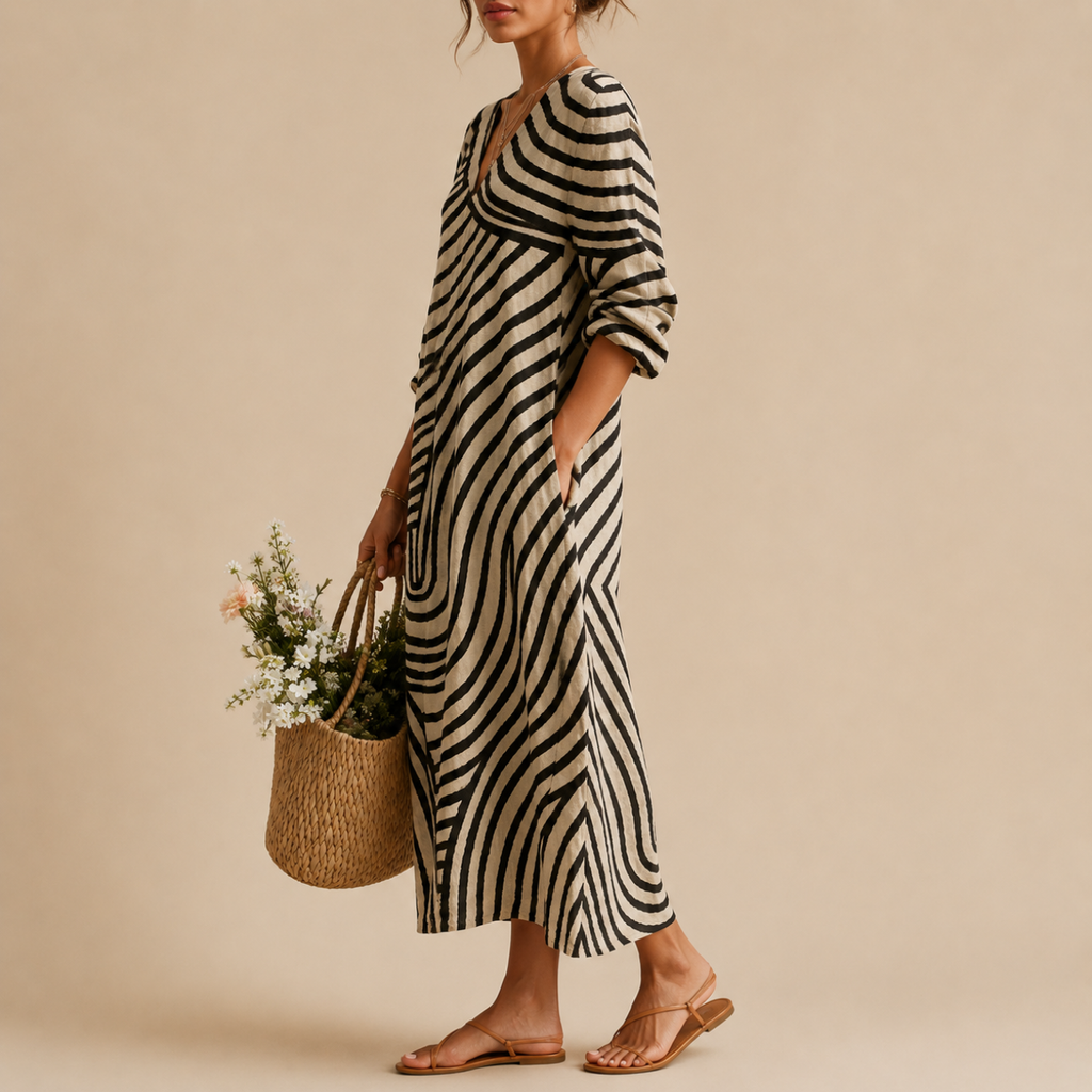 Side view of the Romy Striped Lightweight Vintage Midi Dress featuring an abstract striped patchwork pattern, V-neckline, long sleeves, practical pockets, and a relaxed flowing silhouette. Designed by Bella Hudson.