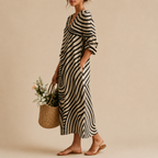 Side view of the Romy Striped Lightweight Vintage Midi Dress featuring an abstract striped patchwork pattern, V-neckline, long sleeves, practical pockets, and a relaxed flowing silhouette. Designed by Bella Hudson.