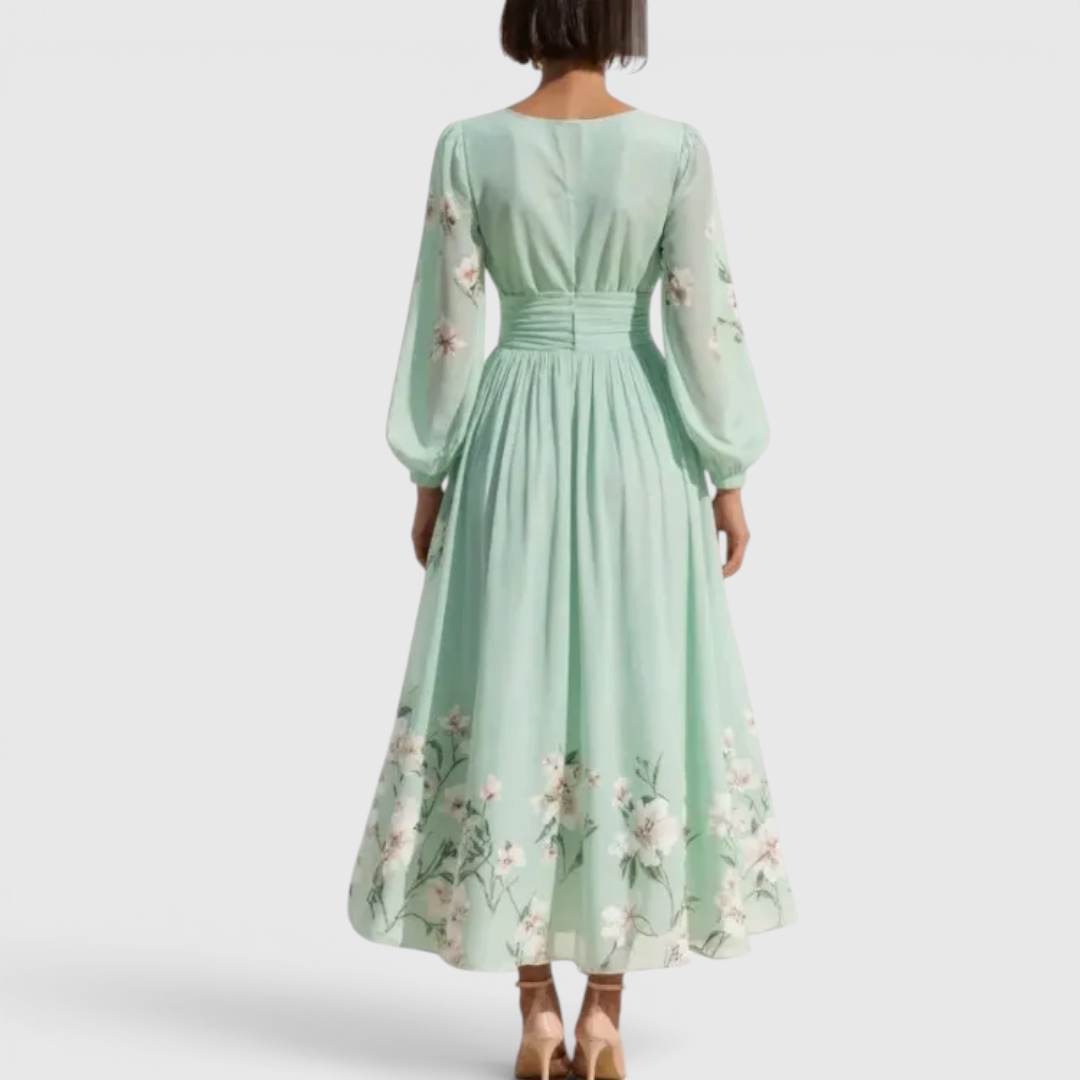 Back view of the Rosalie Midi Dress Floral-Print Chiffon Pleated V-Neck in light green, highlighting the long bishop sleeves, flowing pleated skirt, and elegant floral-print silhouette. Designed by Bella Hudson.