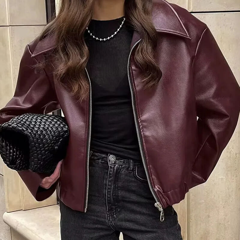 Close-up detail view of the Rosalind Jacket Faux-Leather Cropped in dark brown, featuring the collared neckline, zip-front closure, seam detailing, and smooth faux-leather texture. Designed by Bella Hudson.