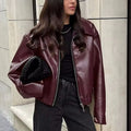 Front view of the Rosalind Jacket Faux-Leather Cropped in dark brown, featuring a collared neckline, zip-front closure, long sleeves, and a relaxed cropped silhouette. Designed by Bella Hudson.