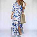 Front view of the Rosamund Shirt Dress Printed Long-Sleeve Button-Front in light blue, featuring a collared neckline, button-front closure, abstract print, side slit, and a flowing maxi silhouette. Designed by Bella Hudson.