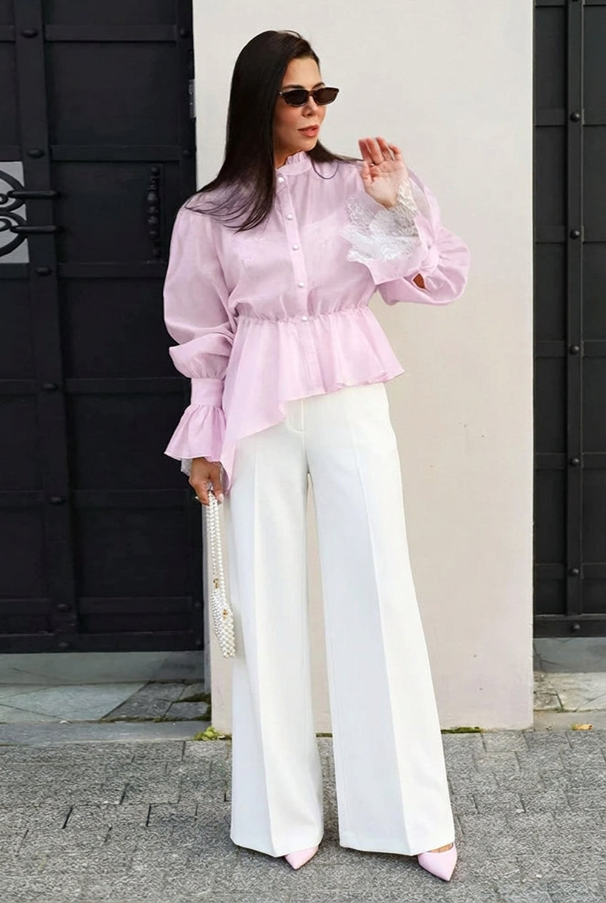 Sabrina Pink ruffle-hem blouse with gathered waist and lace-trim cuffs styled with white wide-leg pants.