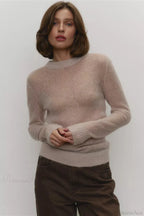 Selena Beige sheer-knit crewneck sweater styled with brown wide-leg jeans, showing the relaxed fit and ribbed cuffs.