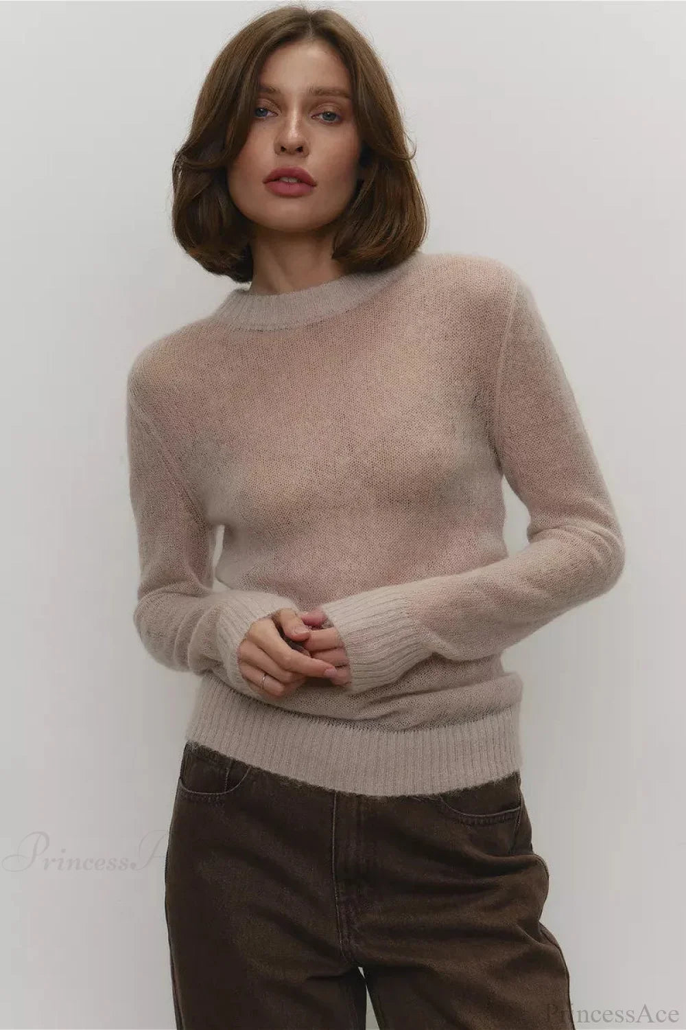 Selena Beige sheer-knit crewneck sweater styled with brown wide-leg jeans, showing the relaxed fit and ribbed cuffs.