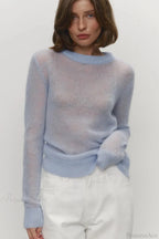 Selena Blue sheer-knit crewneck sweater worn with white jeans, showing the light, airy knit and ribbed trim.