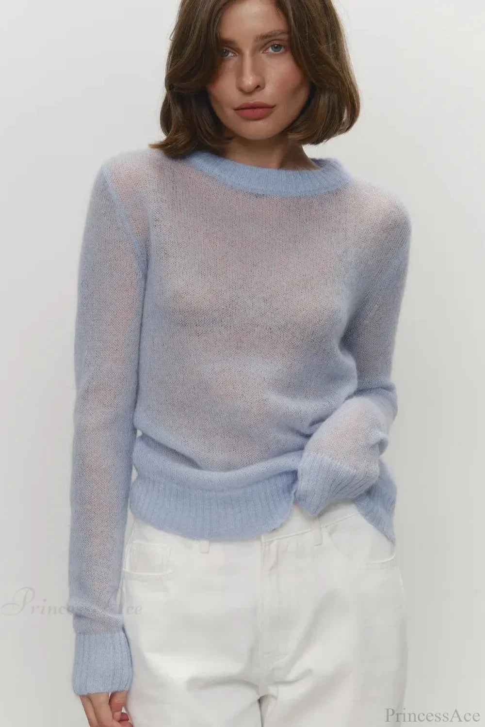 Selena Blue sheer-knit crewneck sweater worn with white jeans, showing the light, airy knit and ribbed trim.