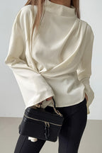 Selene Apricot blouse close-up of the draped front and flared sleeve with a black handbag.