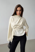Selene Apricot blouse shown from the front with a crossover drape, gathered waist and long flared sleeves.