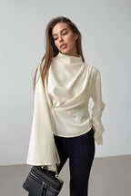 Selene Apricot draped mock neck blouse with flared sleeves styled with black pants and a black handbag.