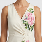 Close-up detail of the Seraphine Maxi Dress Floral-Print Bodycon V-Neck in white, featuring the V-neckline, wrap-style bodice, and vibrant tropical floral print. Designed by Bella Hudson.