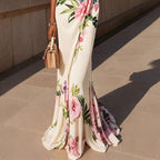 Lifestyle lower view of the Seraphine Maxi Dress Floral-Print Bodycon V-Neck in white, showcasing the fitted silhouette, floral print, and flowing fishtail maxi hem. Designed by Bella Hudson.