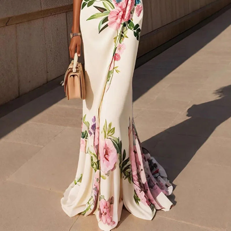 Lifestyle lower view of the Seraphine Maxi Dress Floral-Print Bodycon V-Neck in white, showcasing the fitted silhouette, floral print, and flowing fishtail maxi hem. Designed by Bella Hudson.