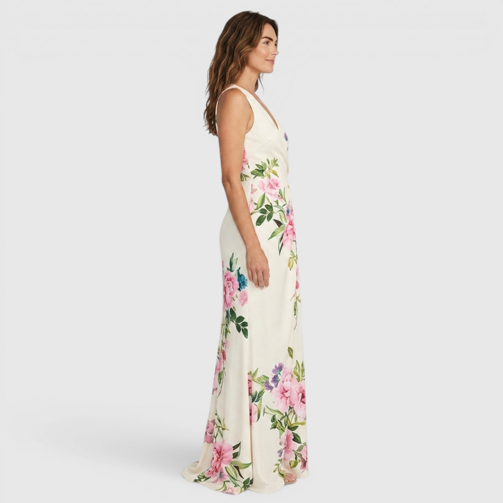 Side view of the Seraphine Maxi Dress Floral-Print Bodycon V-Neck in white, showcasing the flattering bodycon fit, sleeveless V-neck design, floral print, and elegant fishtail hem. Designed by Bella Hudson.