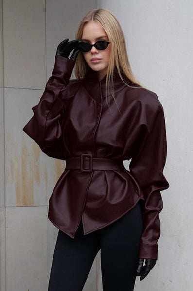 Serena Red faux leather belted jacket shown from a three-quarter angle with a high neckline, structured shoulders, and defined waist