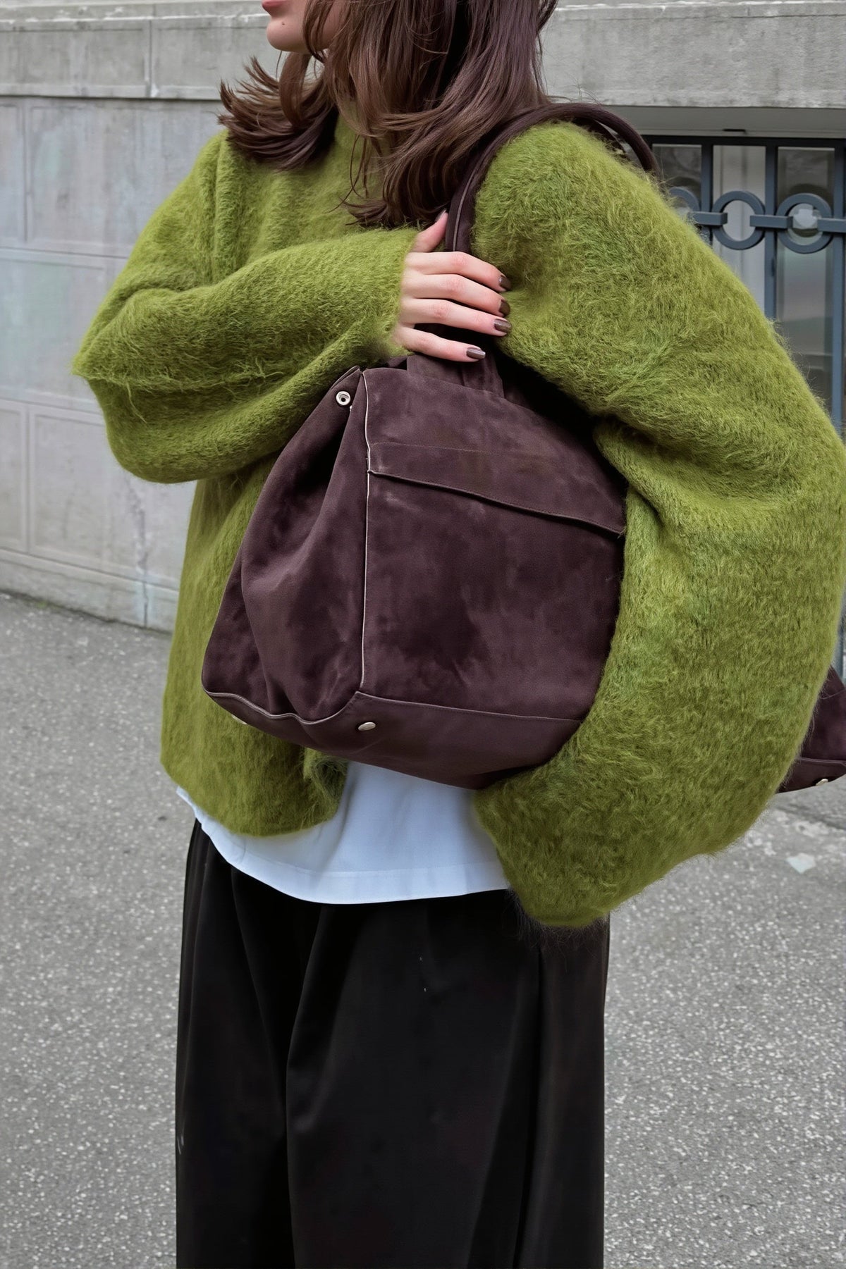 Sienna Green extra-fuzzy oversized sweater layered over a white tee with a brown suede tote.