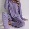 Sloane Purple ribbed two-piece lounge set with a V-neck long-sleeve top and matching wide-leg pants shown in a relaxed seated pose