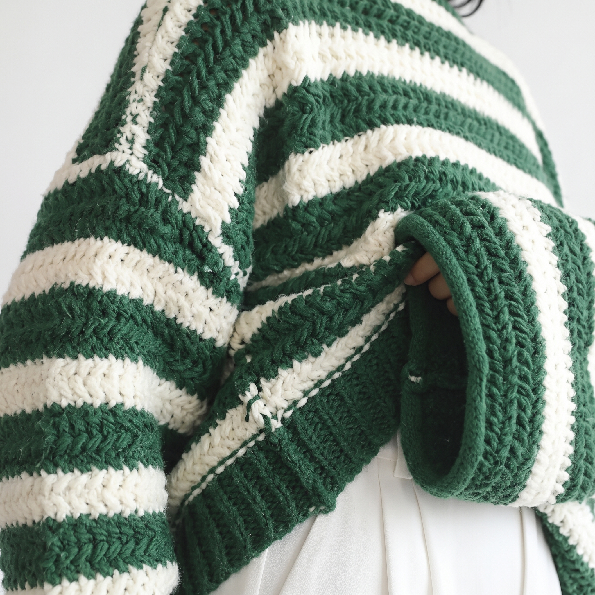 Close-up detail view of the Solange Sweater Chunky-Knit Striped in green and white, highlighting the thick knit texture, horizontal stripe pattern, and ribbed sleeve detailing. Designed by Bella Hudson.