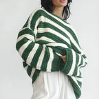 Front view of the Solange Sweater Chunky-Knit Striped in green, featuring wide green and white horizontal stripes, a round neckline, long sleeves, chunky knit texture, and an oversized relaxed silhouette. Designed by Bella Hudson.