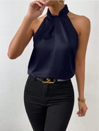 Front view of the Solenne Top Satin Halter Tie-Neck in dark blue, featuring a halter tie neckline, sleeveless silhouette, silky satin fabric, and an elegant relaxed fit. Designed by Bella Hudson.