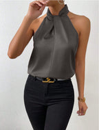 Front view of the Solenne Top Satin Halter Tie-Neck in dark gray, featuring a halter tie neckline, sleeveless design, luxurious satin finish, and a refined draped silhouette. Designed by Bella Hudson.