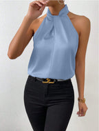Front view of the Solenne Top Satin Halter Tie-Neck in light blue, featuring a halter tie neckline, sleeveless design, silky satin fabric, and a graceful draped silhouette. Designed by Bella Hudson.