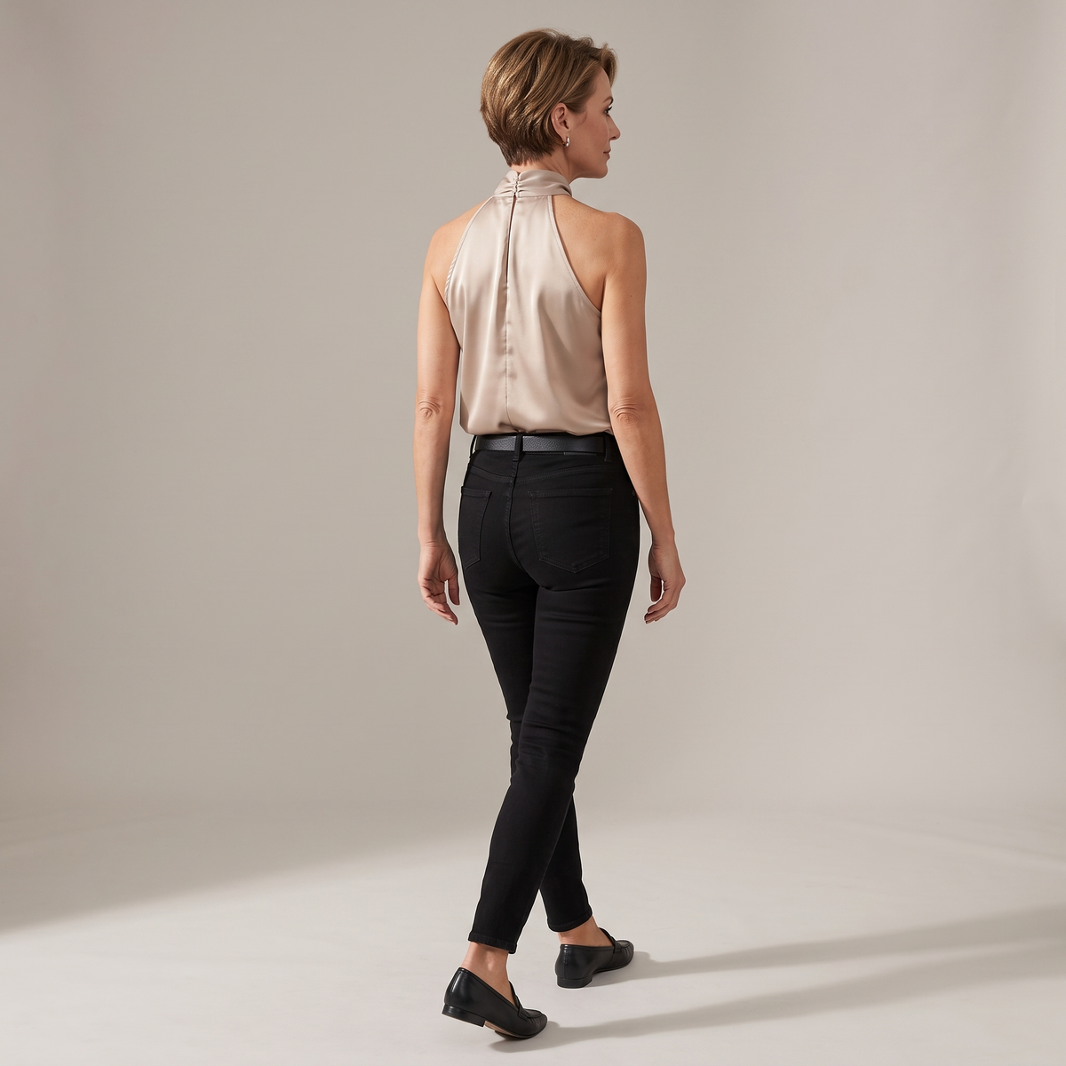 Back view of the Solenne Top Satin Halter Tie-Neck in light brown, highlighting the halter-back design, sleeveless silhouette, and smooth satin finish. Designed by Bella Hudson.
