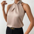 Close-up detail of the Solenne Top Satin Halter Tie-Neck in light brown, featuring the elegant halter tie neckline, soft satin fabric, and graceful draping. Designed by Bella Hudson.