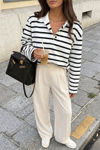 Sophie White striped polo shirt styled with cream pleated trousers, showing the button placket and relaxed fit.